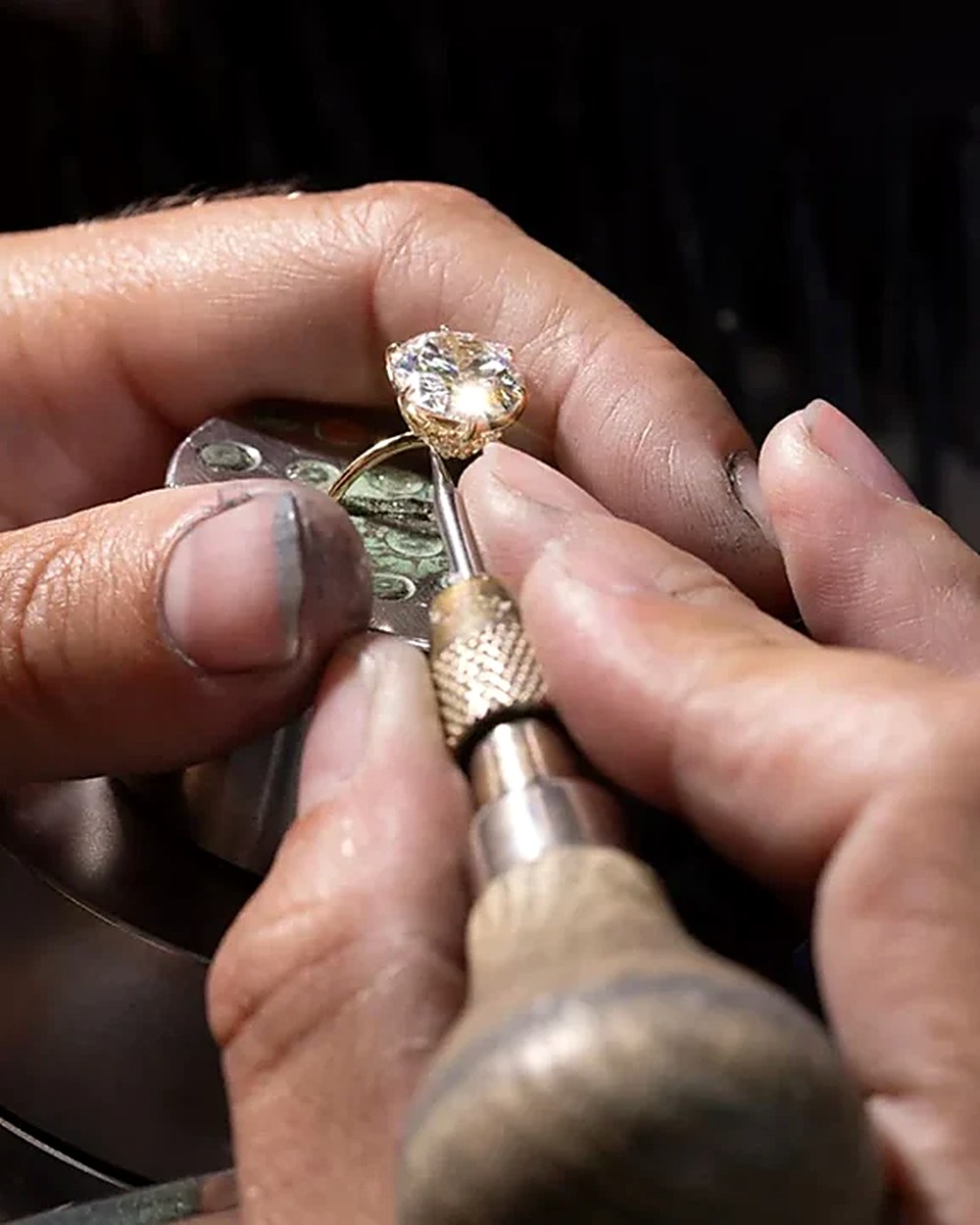 Jeweler setting a diamond into a gold ring by hand